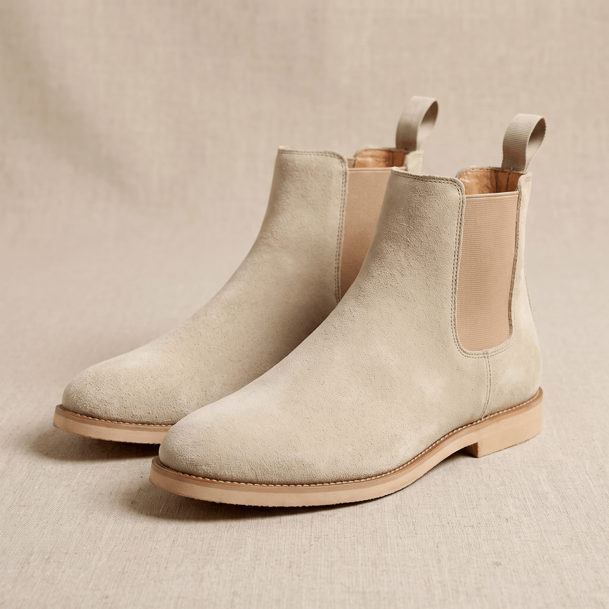 Pair of beige vegan suede Chelsea boots on a neutral background.