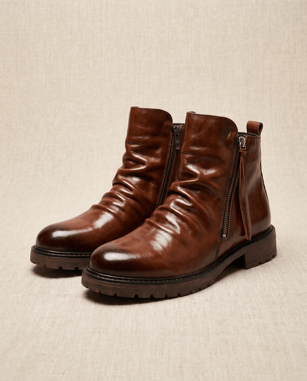 Brown waxed leather boots with a ruched shaft, side zip closure, and a sturdy, slip-resistant lug sole.