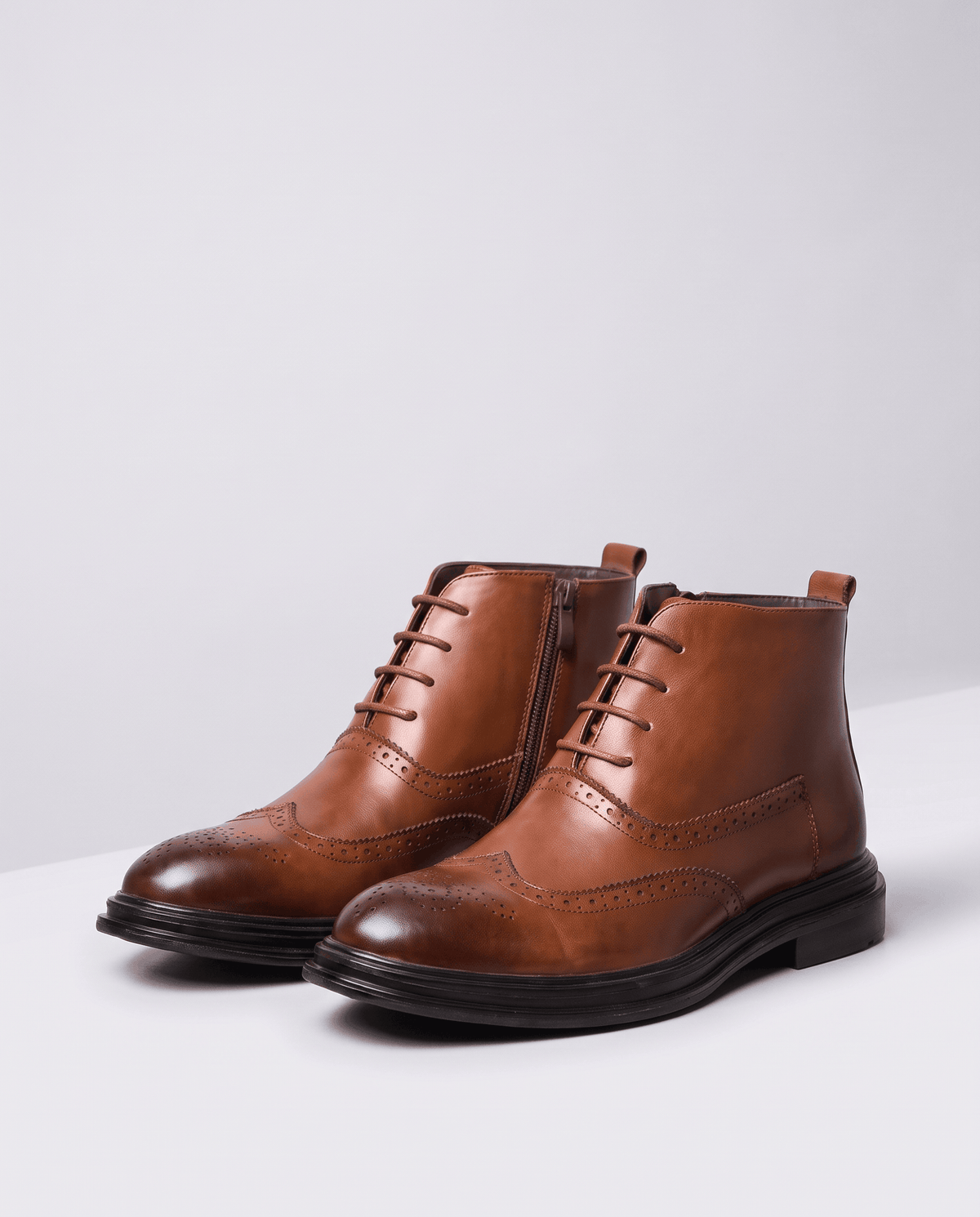 Men's brown wingtip boots with laces and brogue detail, shown as a pair in a studio