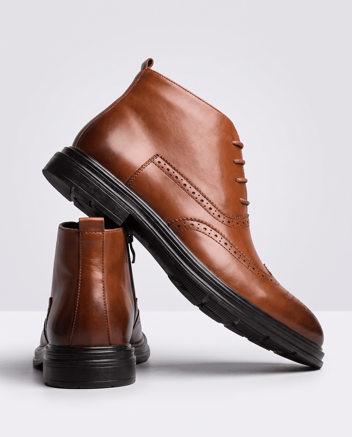 Brown ankle boot tilted to show the rubber outsole, with a second boot beside it