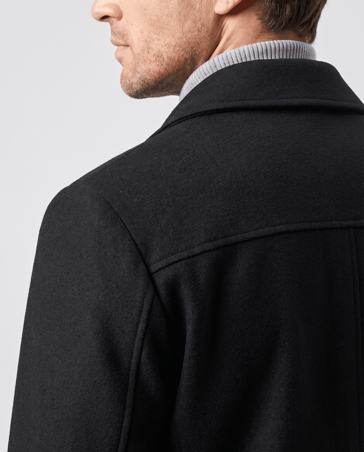 Close crop of the black coat collar and shoulder seam from behind