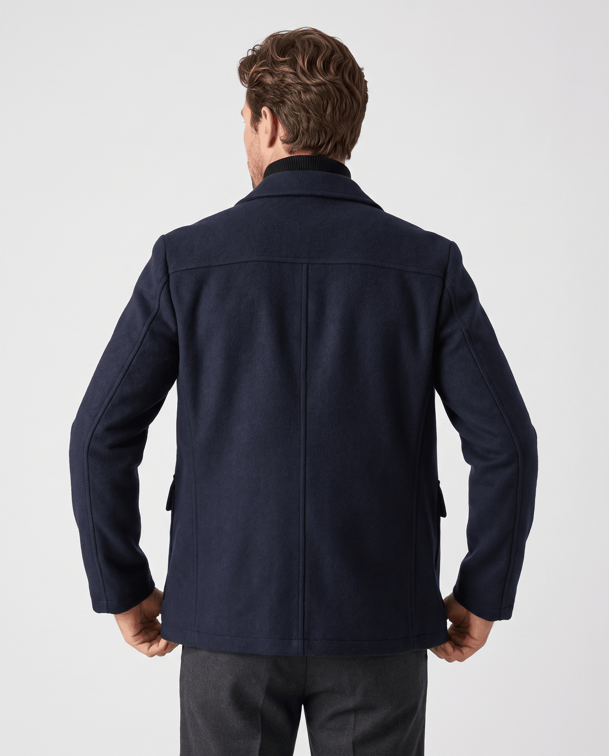 Back view of the navy coat showing the straight hem at the thigh