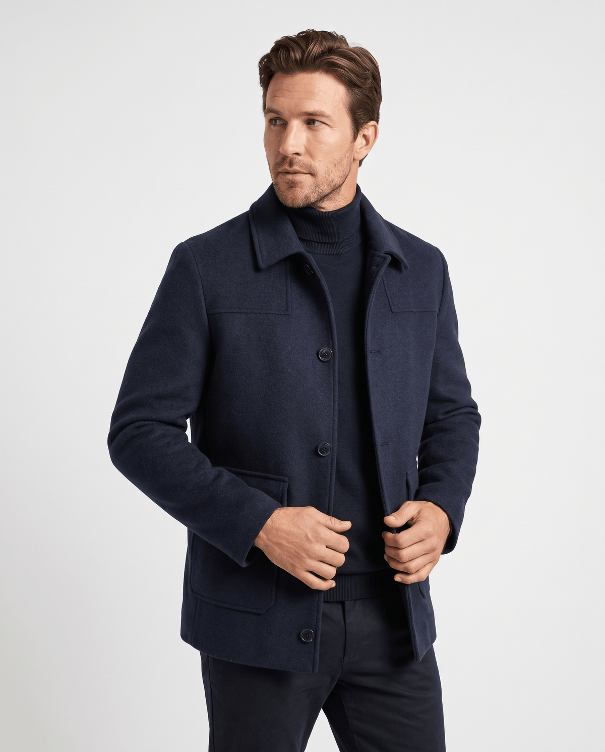 Navy car coat worn open over a dark knit, model facing forward