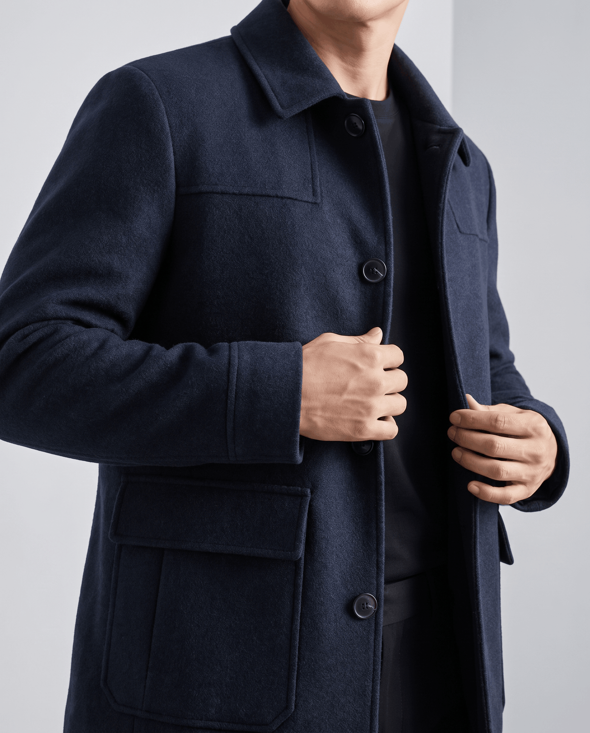 Model fastening the navy coat at chest height, lapel folded flat