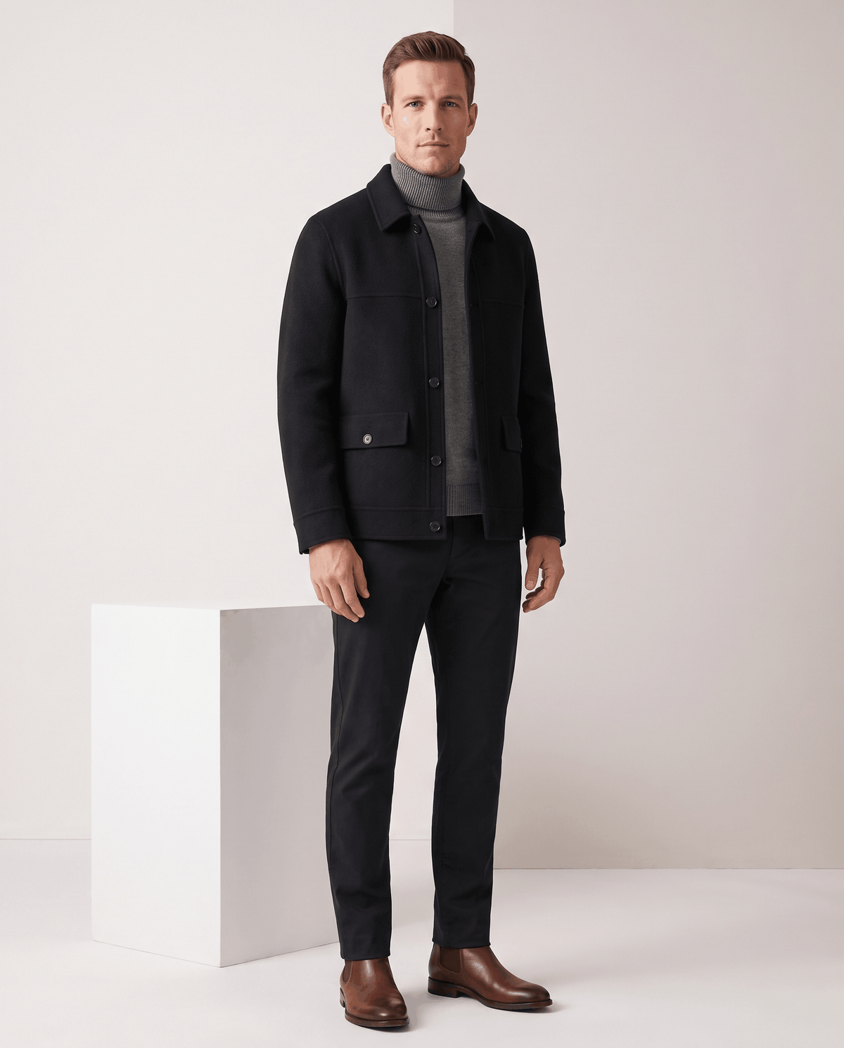 Full-length black jacket styled with black trousers and brown Chelsea boots