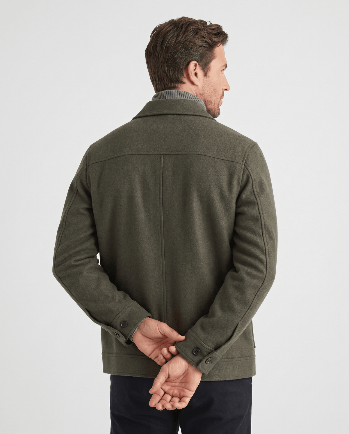 Back view of an olive green jacket showing the center seam and hem tabs