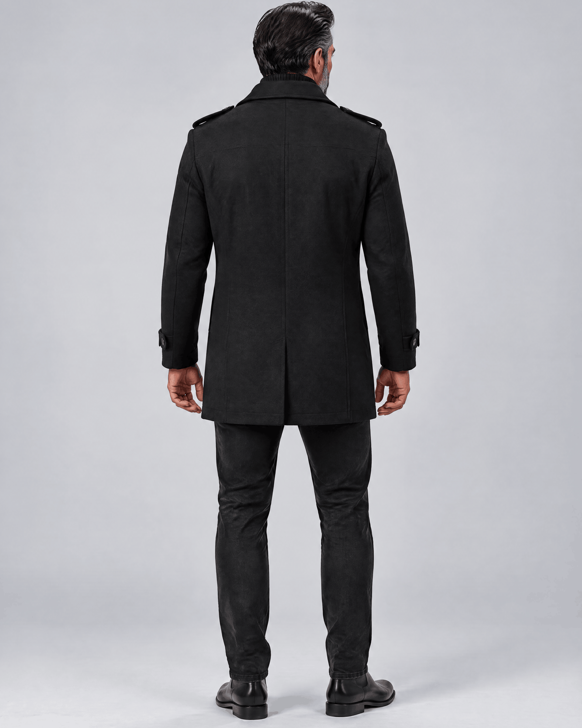 Back of the black coat showing a plain back panel and clean shoulder line over dark trousers