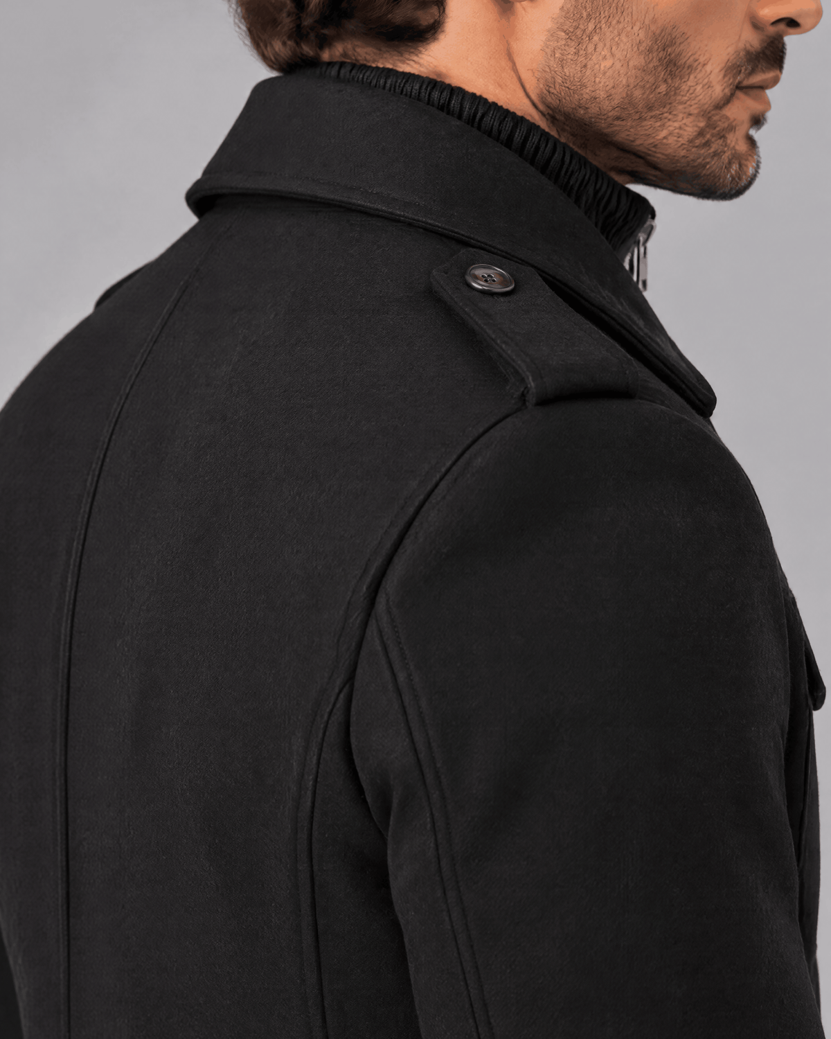 Black coat shoulder and collar close-up showing the epaulette and textured fabric
