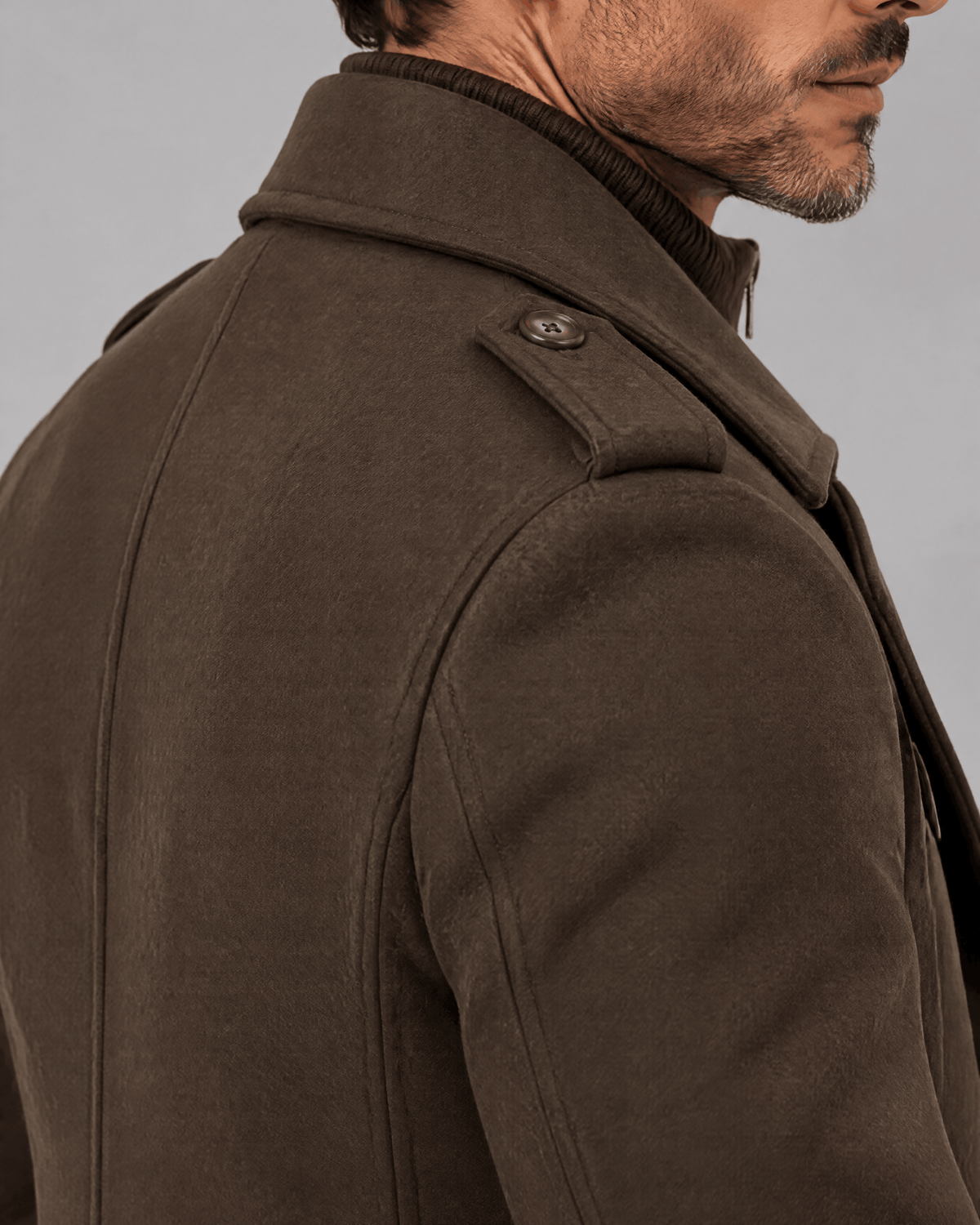 Brown coat shoulder and collar close-up showing the epaulette and woven texture