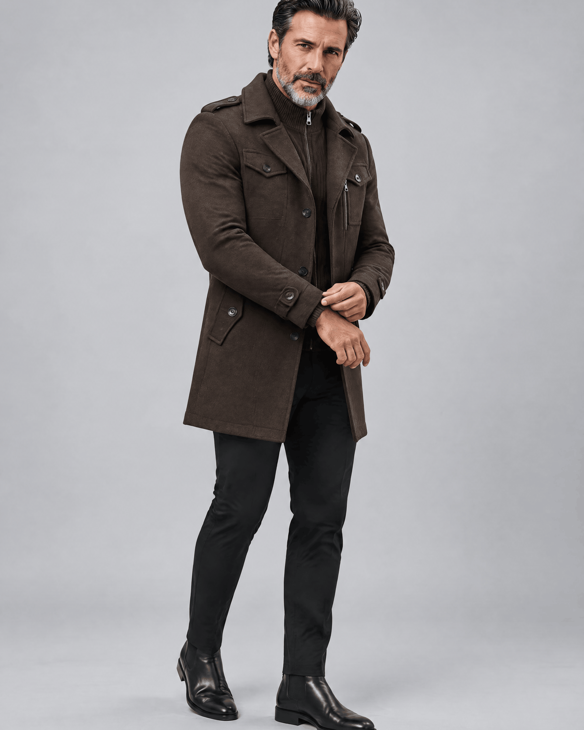 Brown coat in a three-quarter view with one hand at the waist and dark boots