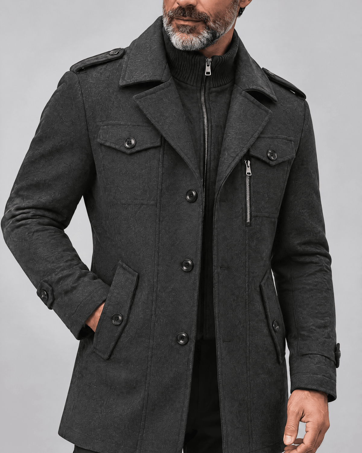 Close-up of the gray coat's chest pockets, zip bib and epaulettes with one hand at the collar