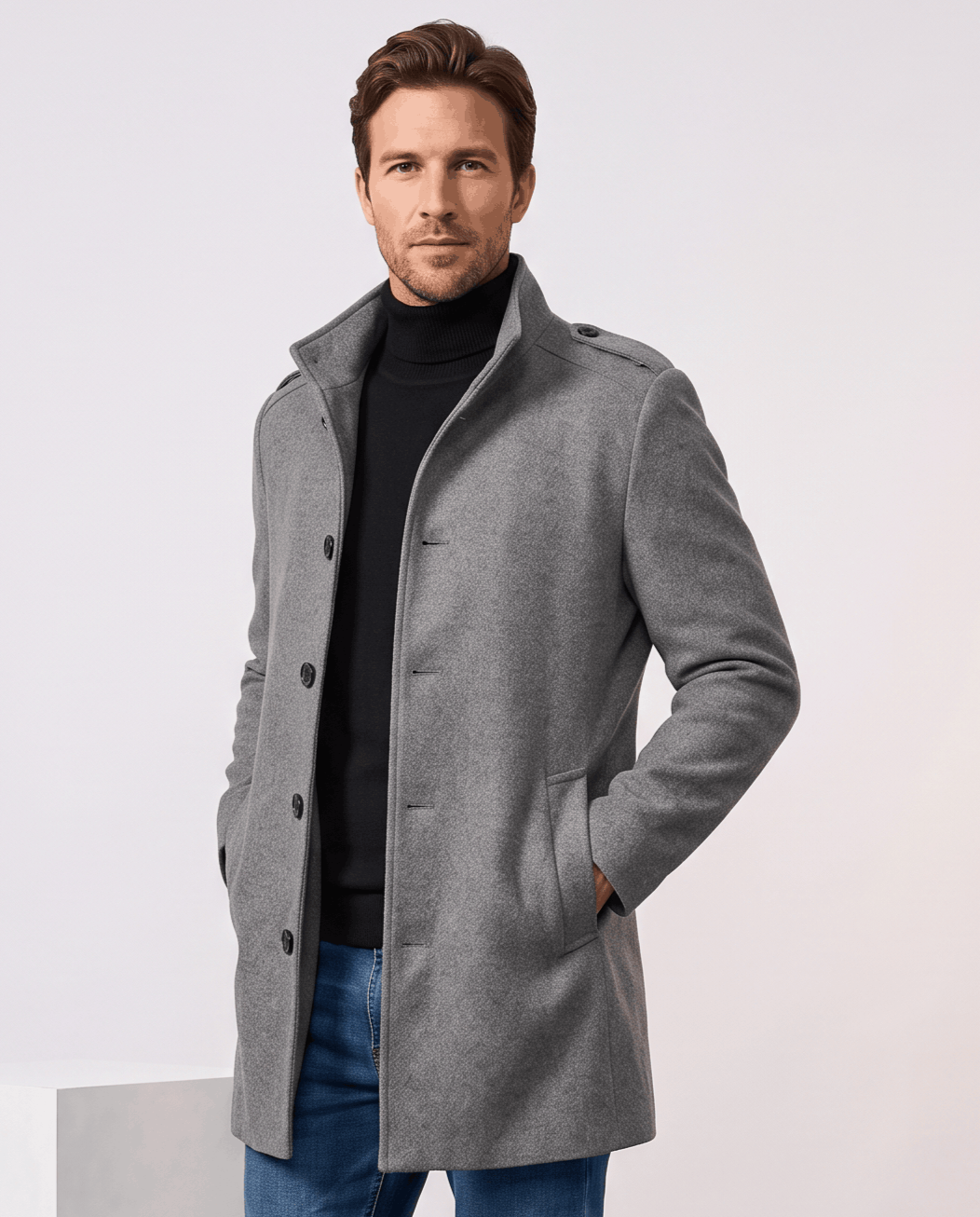 Men's wool blend overcoat in gray with stand collar and epaulettes, worn over a black turtleneck