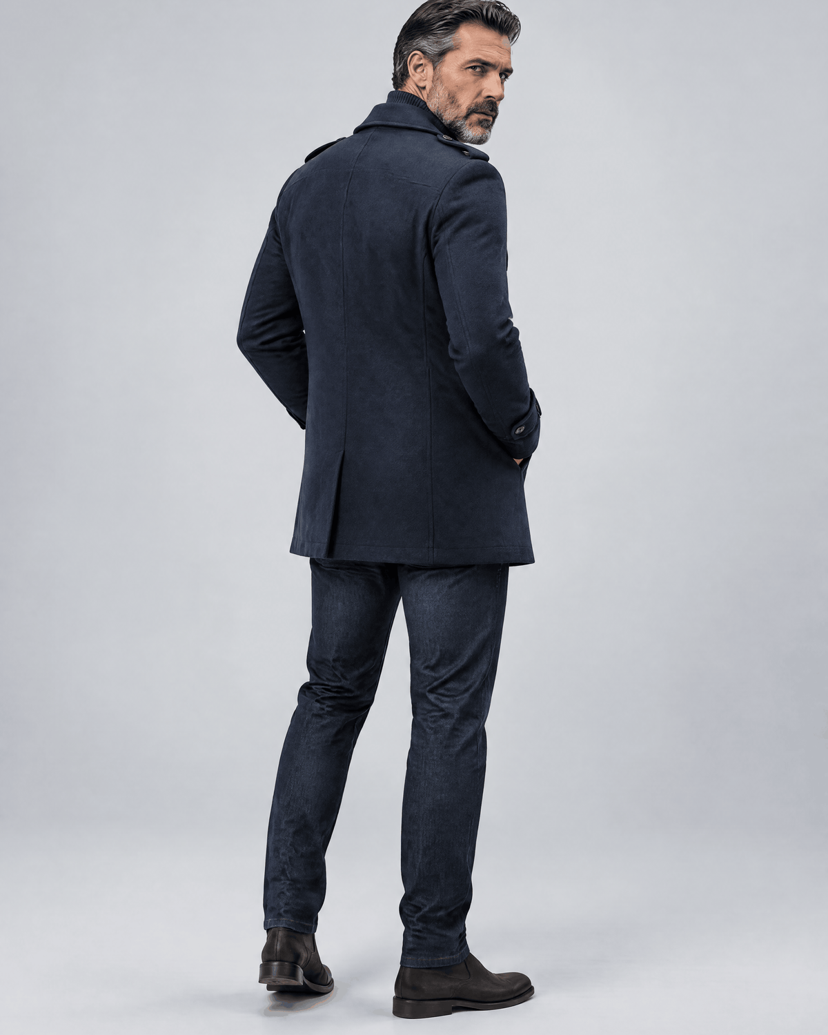 Back of the navy coat showing a clean back panel and the length over dark trousers