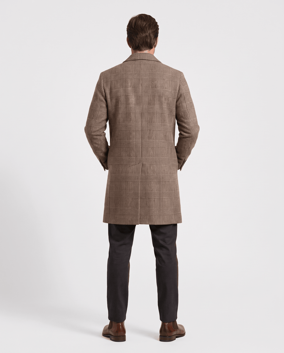 Rear view of the taupe overcoat's straight back panel and hem, worn with dark trousers