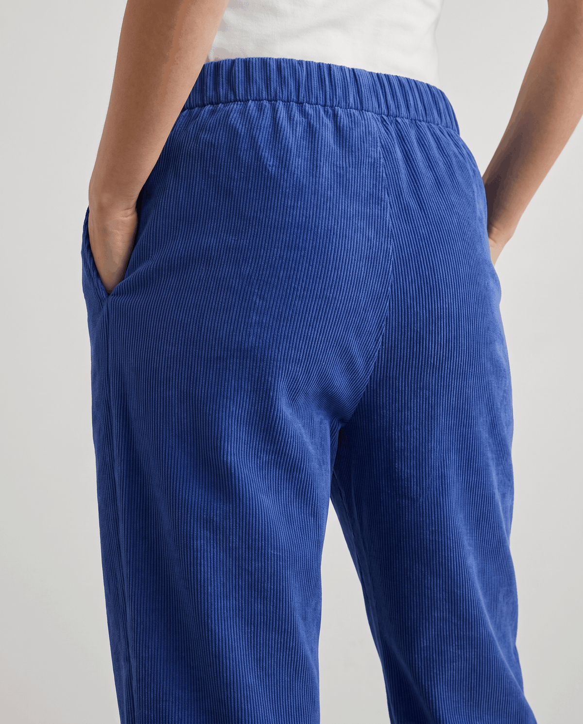 Side close-up of blue pants showing the elastic back waistband and vertical ribbed texture