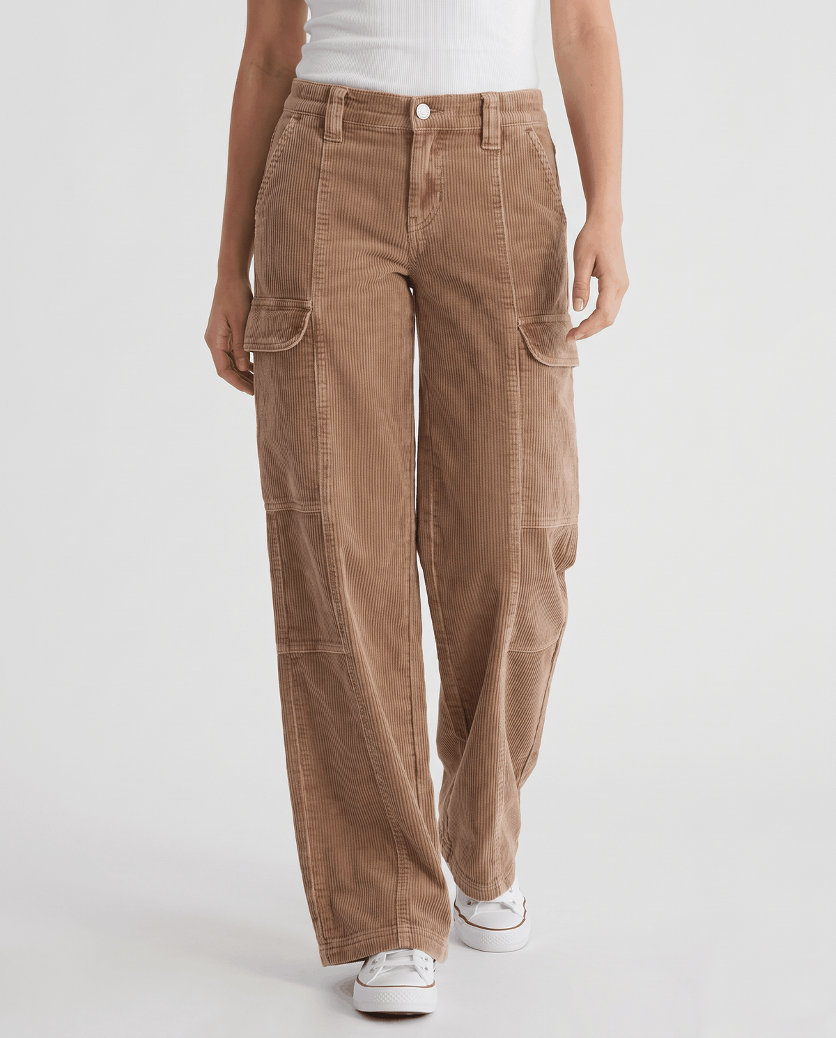Front view of camel corduroy trousers with seamed legs, cargo pockets and white sneakers