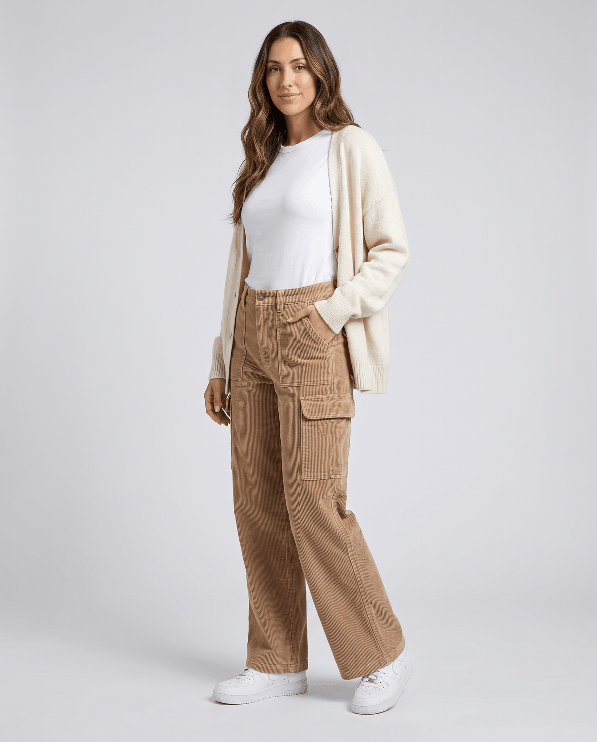 Model in tan cargo trousers styled with a cream cardigan, white tee and white sneakers