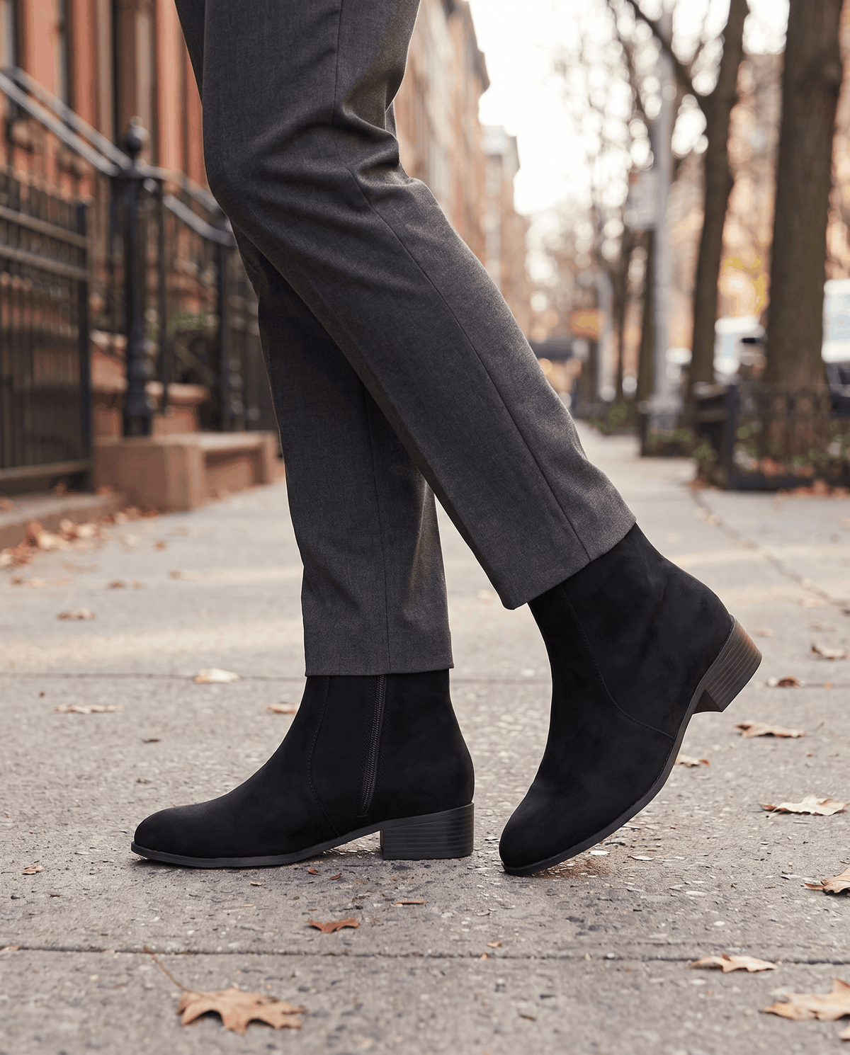 Black suede-look ankle boots worn with grey trousers outdoors