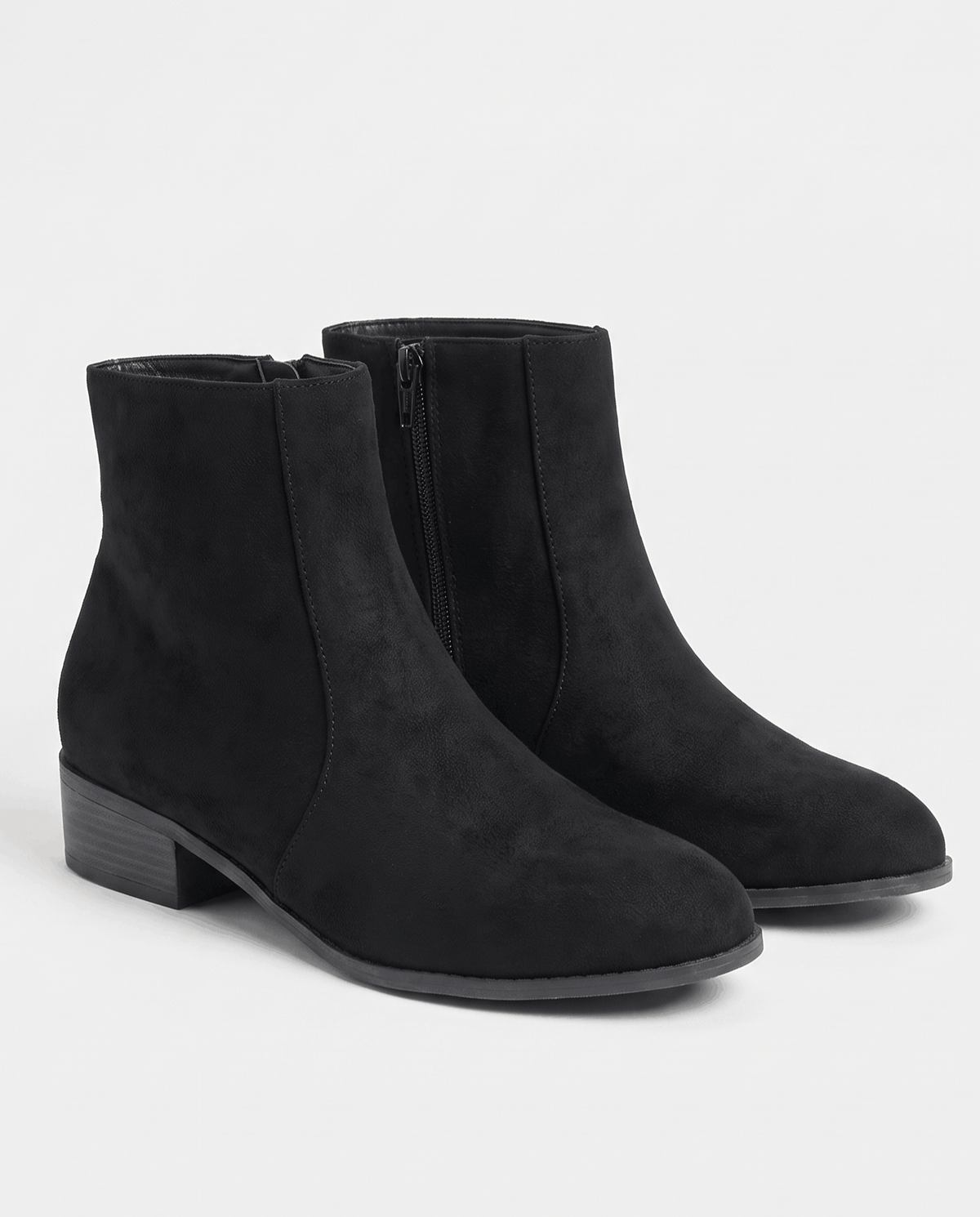 Pair of black suede-look ankle boots angled on a studio backdrop