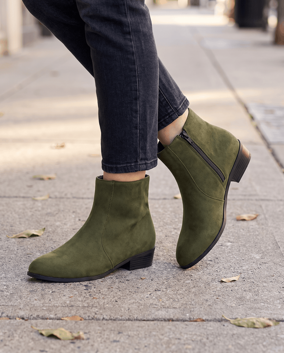 Olive green suede-look ankle boots worn with dark jeans outdoors