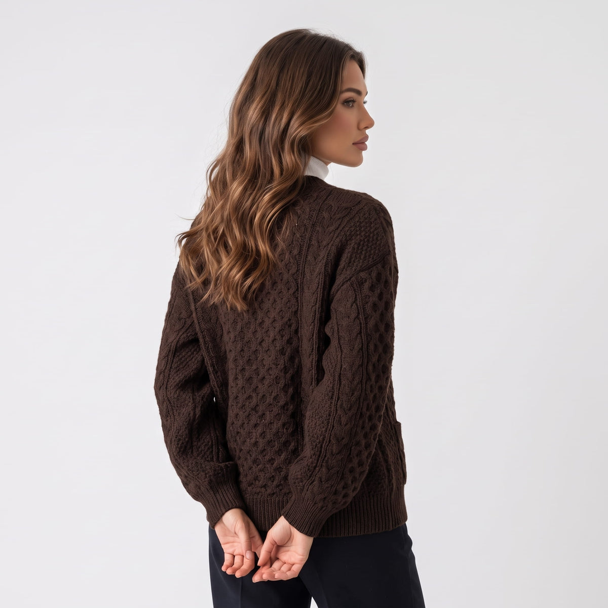 Back view of dark brown cable-knit cardigan worn with dark trousers