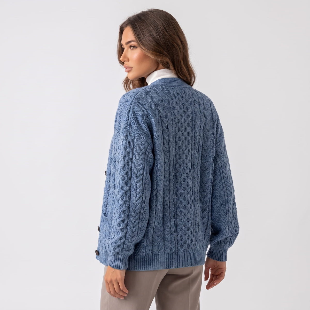 Back view of sky blue cable-knit cardigan worn with taupe trousers
