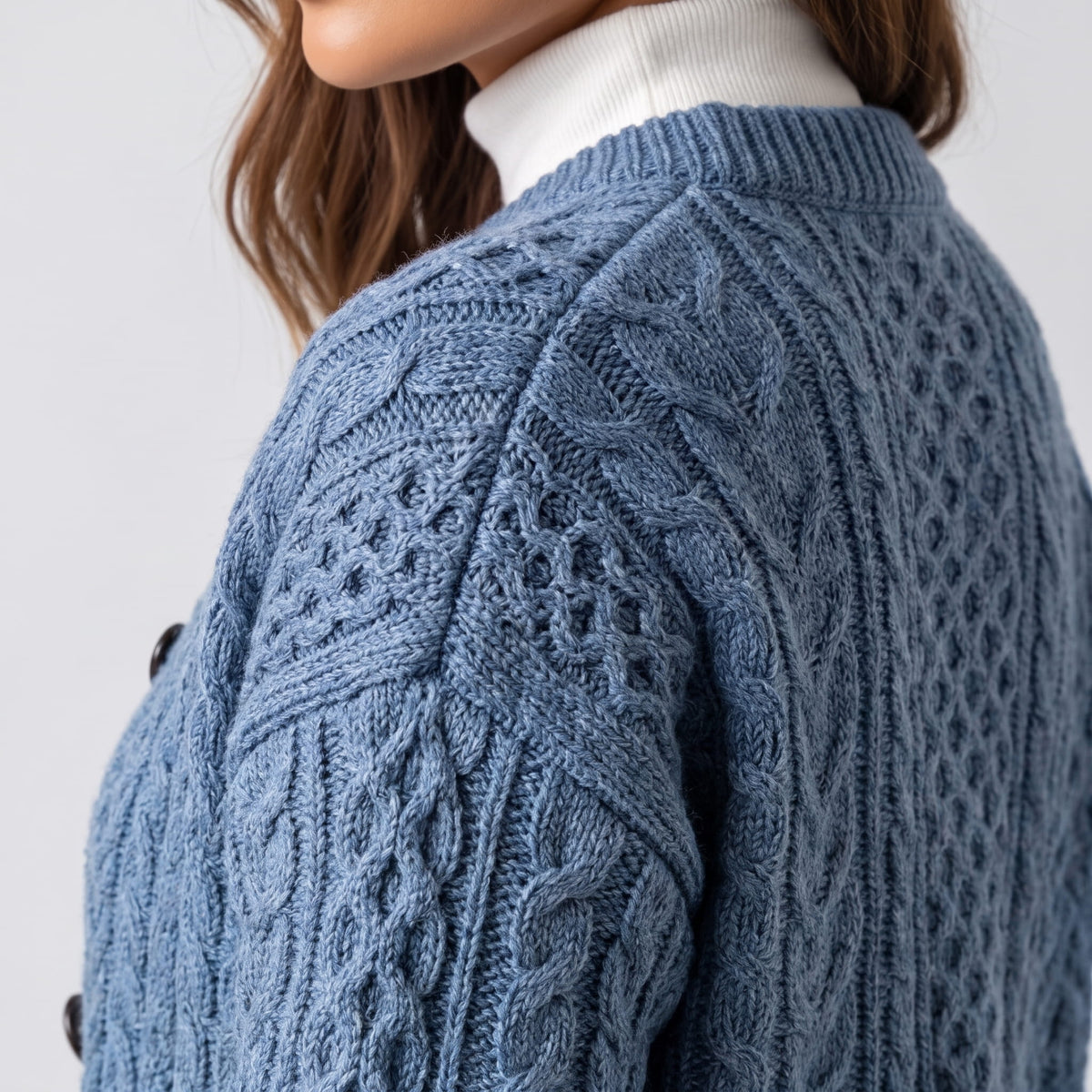 Close side view of sky blue cable-knit cardigan sleeve and shoulder