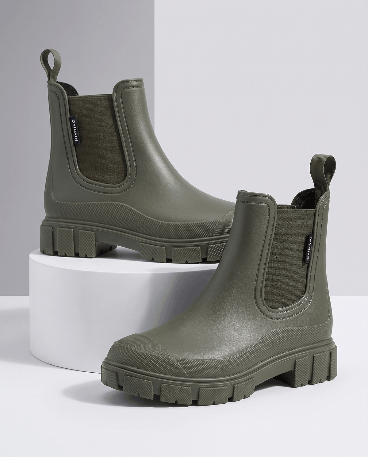Green Chelsea-style ankle boots with chunky lug soles displayed on white blocks.