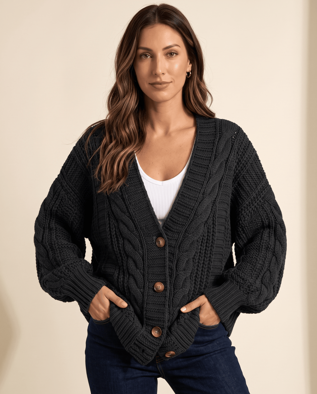 Woman wearing a charcoal cable knit cardigan with hands in the front pockets