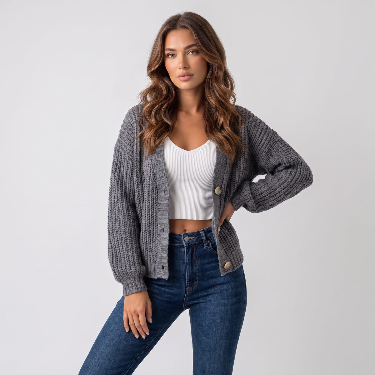 Gray chunky knit cardigan worn open over a white top and blue jeans