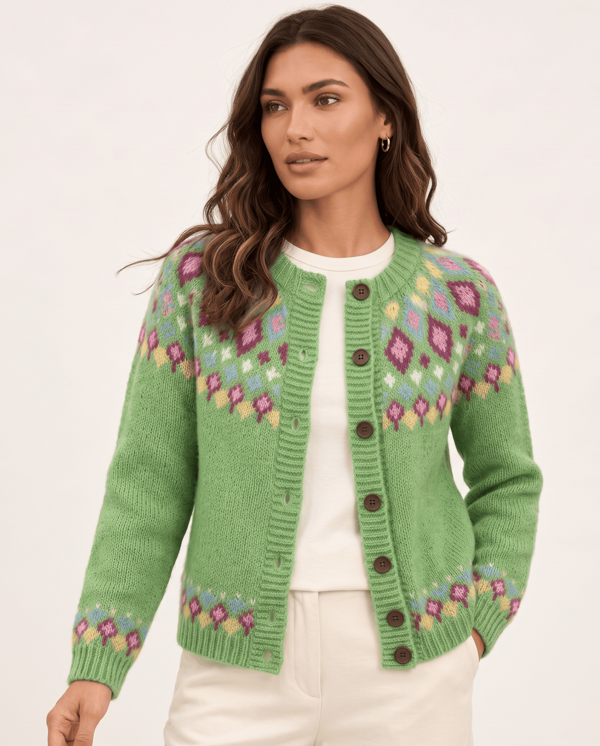 Woman wearing a green Fair Isle yoke cardigan with cream trousers, front view