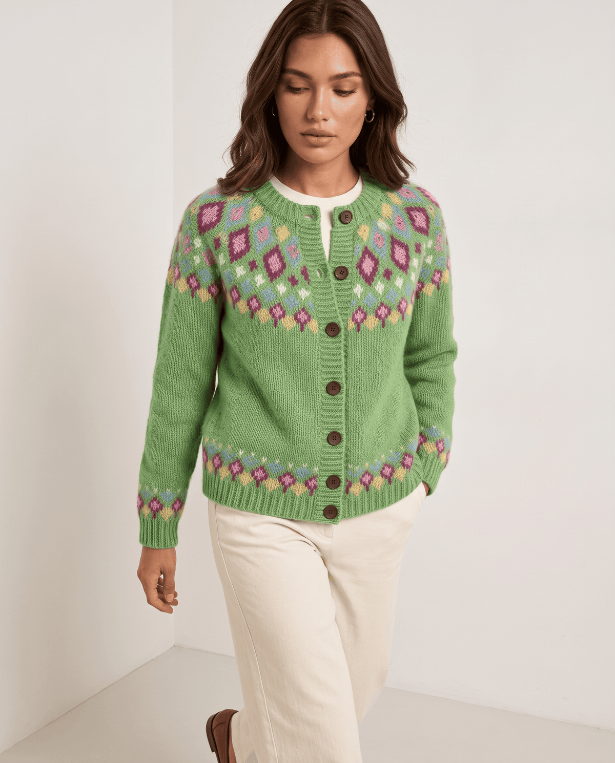 Three-quarter view of a green Fair Isle cardigan with a patterned yoke and cream trousers