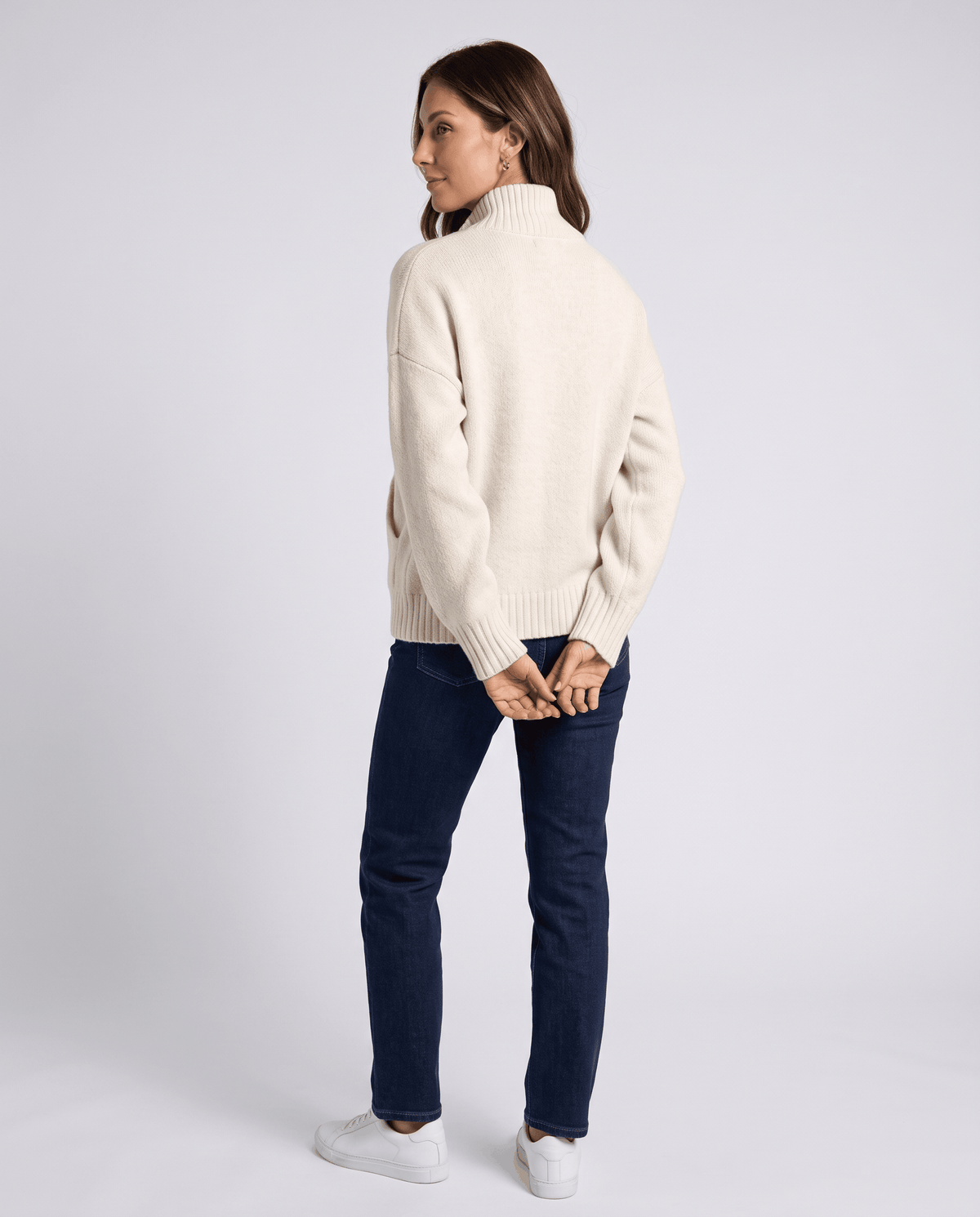 Back view of a beige zip up cardigan with dropped shoulders and ribbed hem