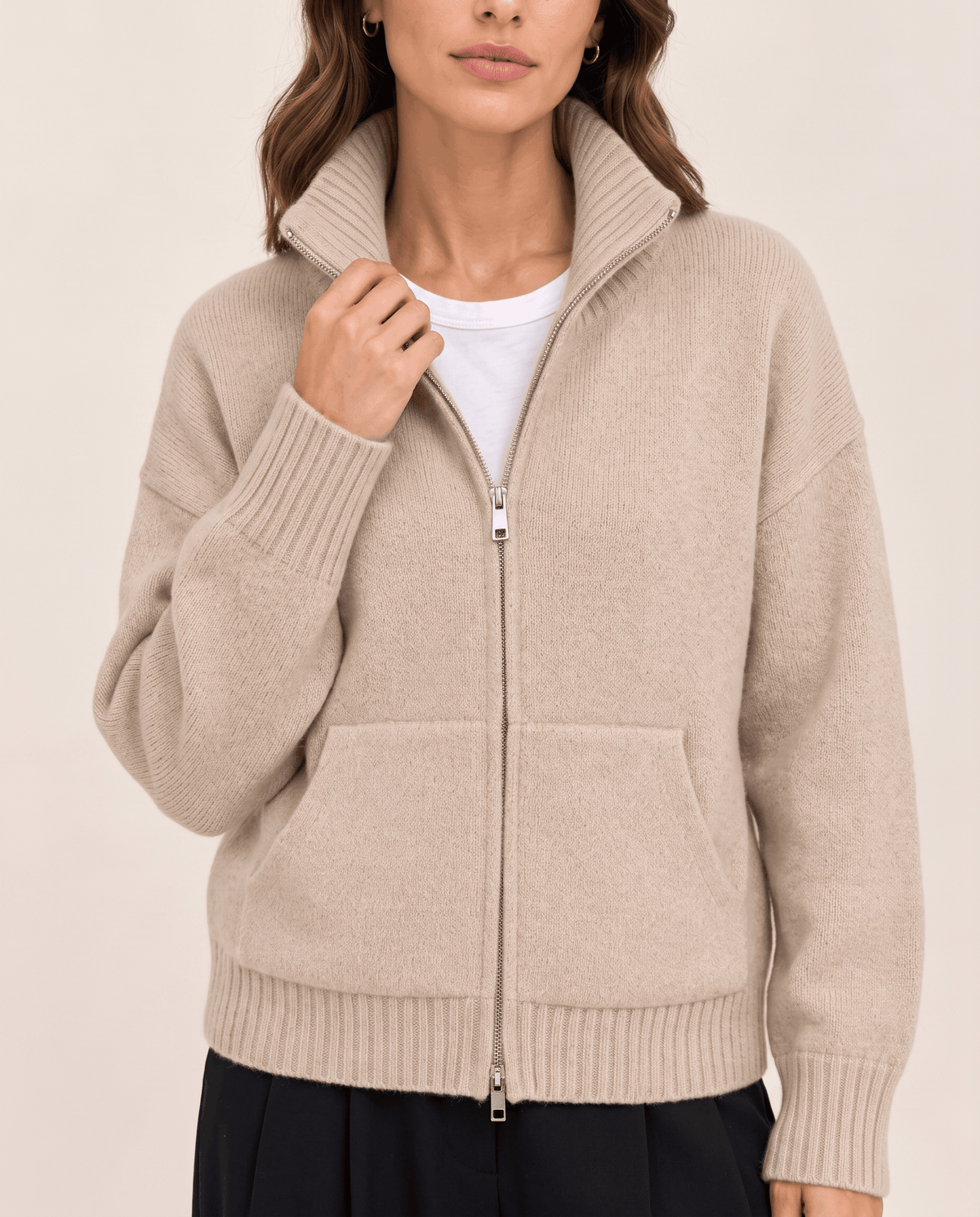 Close-up of beige soft knit, zip and ribbed cuff detail