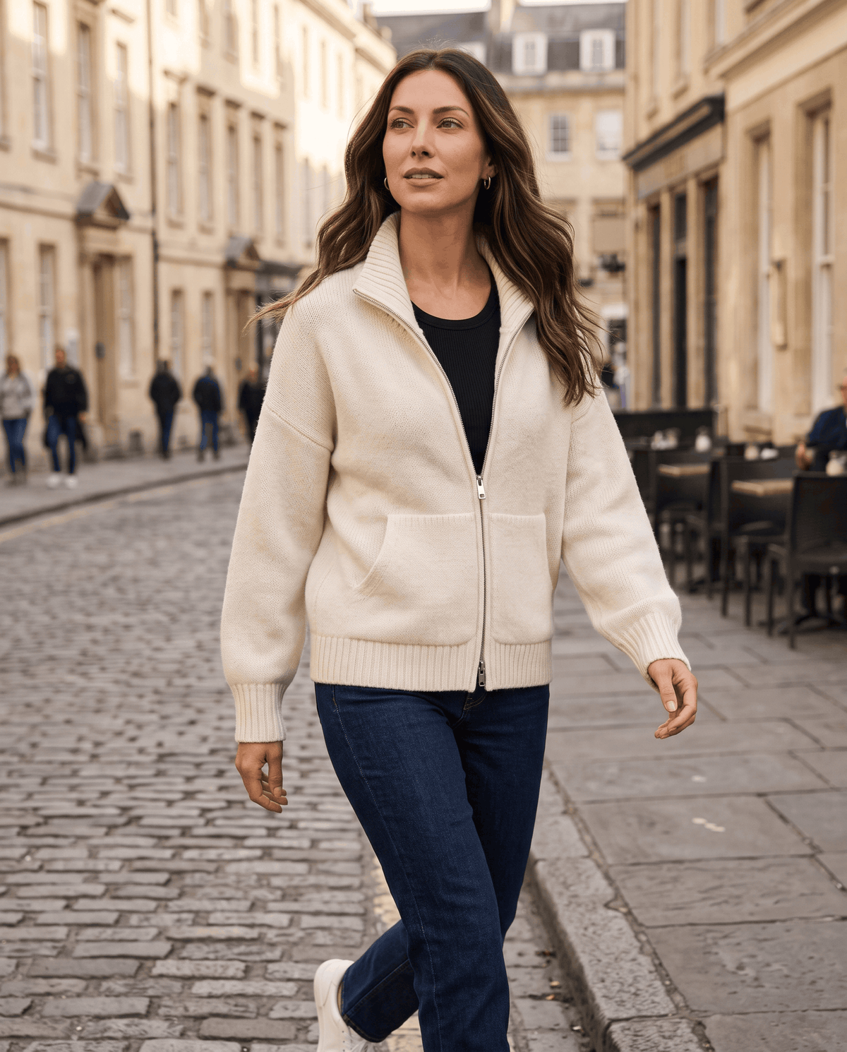 Cream zip up cardigan styled with jeans on a city street