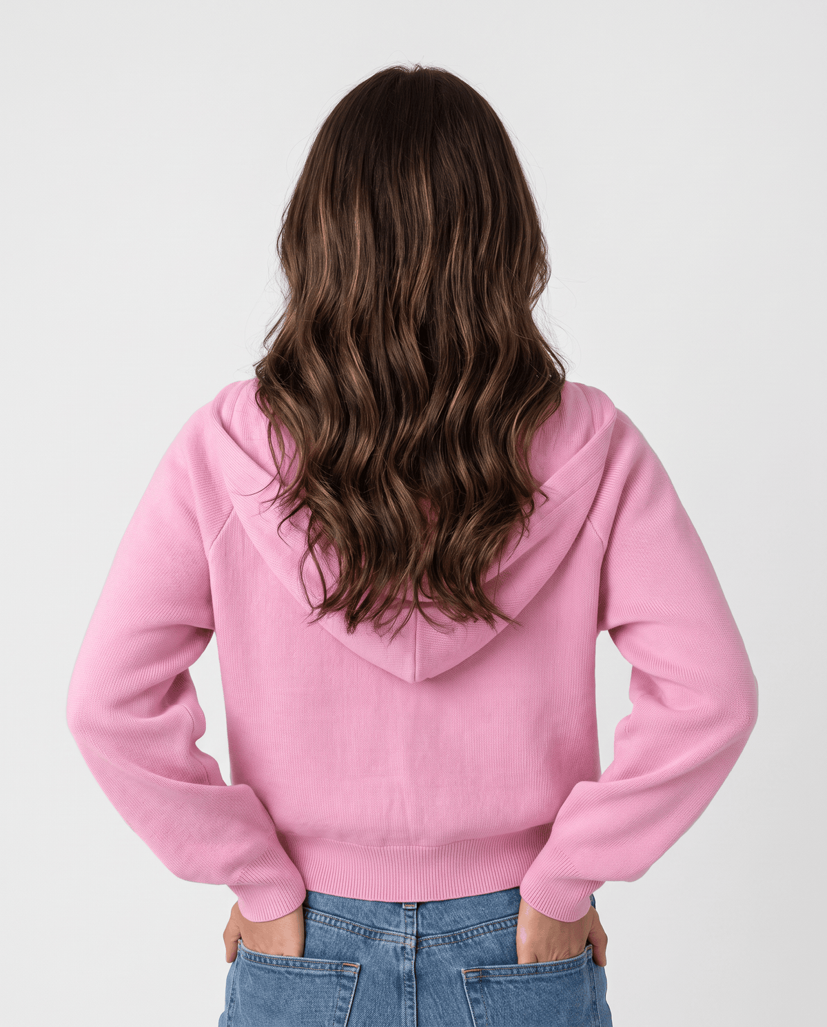 Back view of the pink cropped hoodie with long sleeves and hood resting down