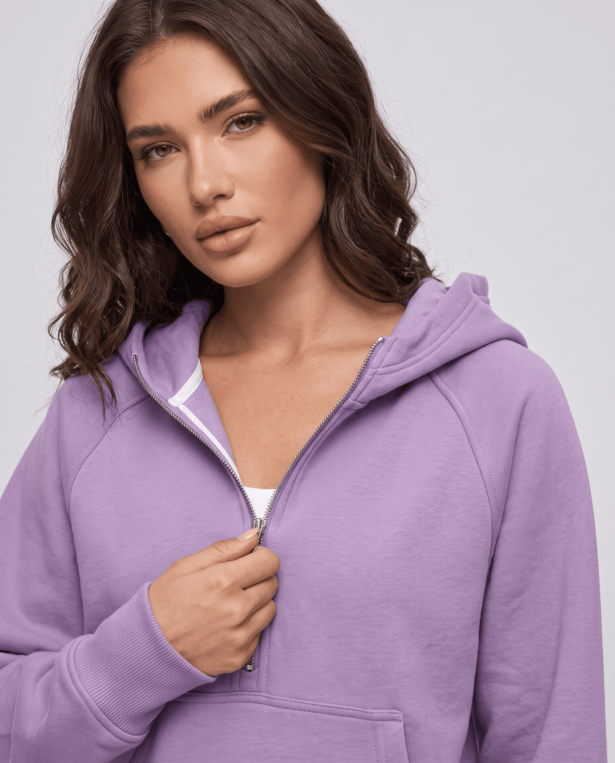 Purple half zip hoodie with a hand on the zipper pull above the front pocket