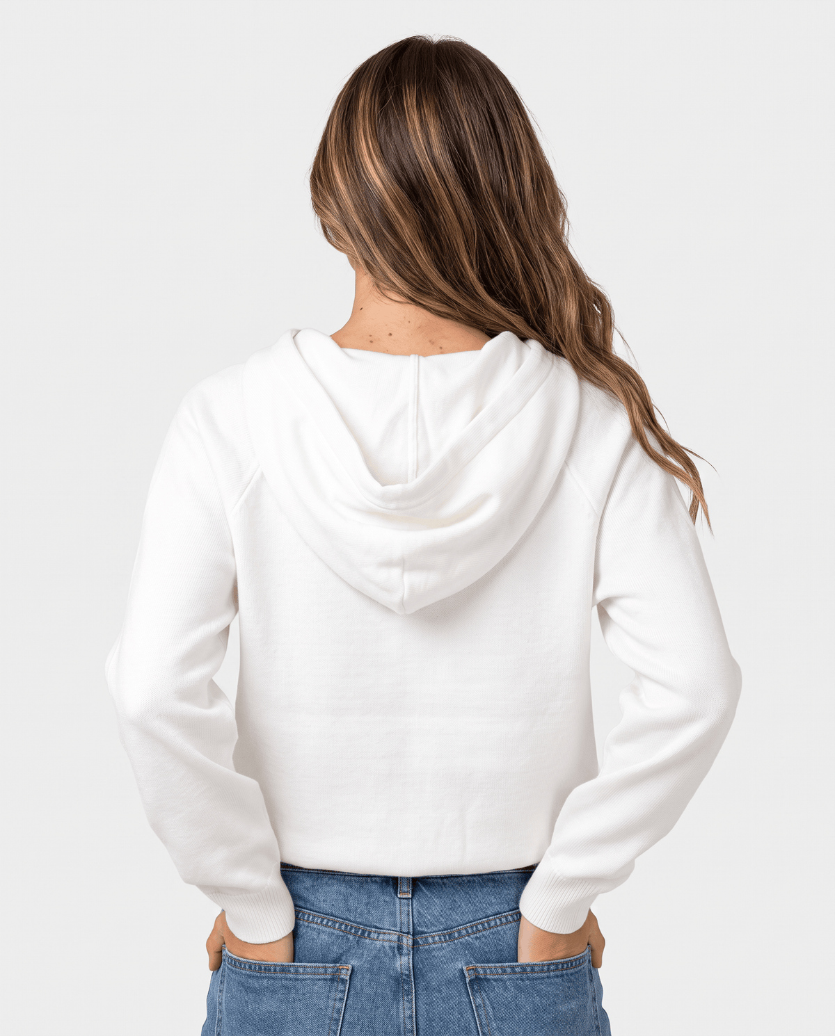 Back view of the white cropped hoodie with the hood down over jeans