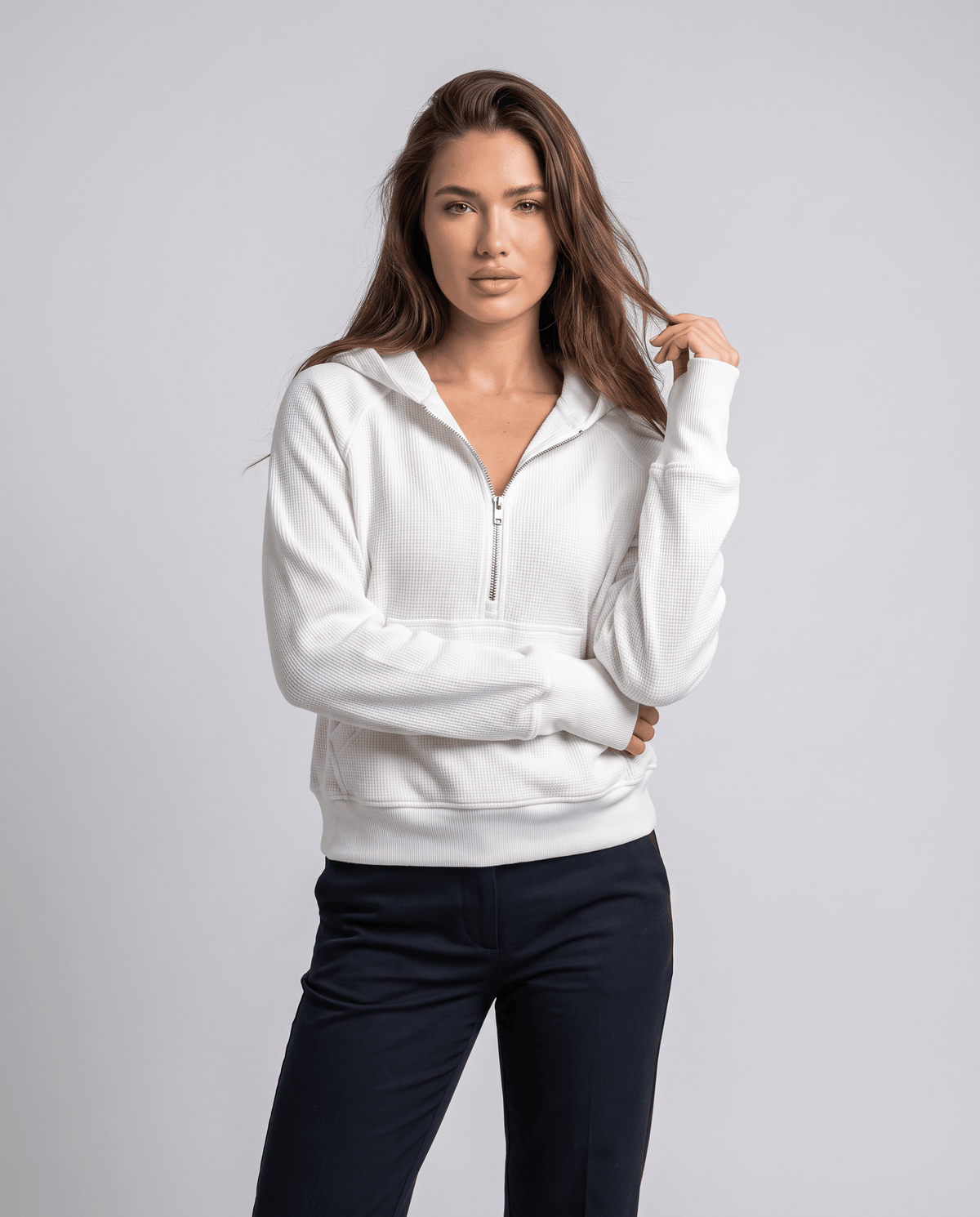 White half zip hoodie styled with dark pants and the hood resting at the back