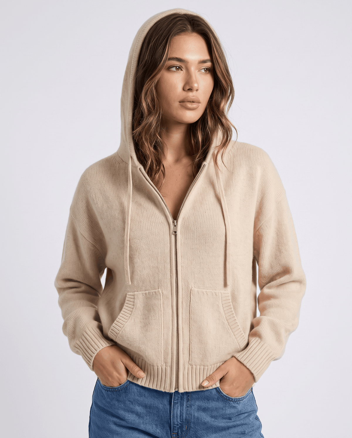 Front view of beige zip-up knit cardigan with the hood up and drawstrings
