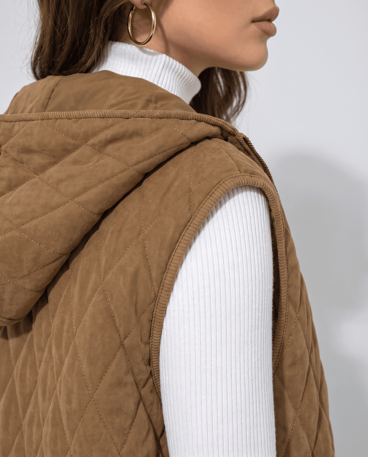Close side view of brown quilted vest hood and diamond stitching