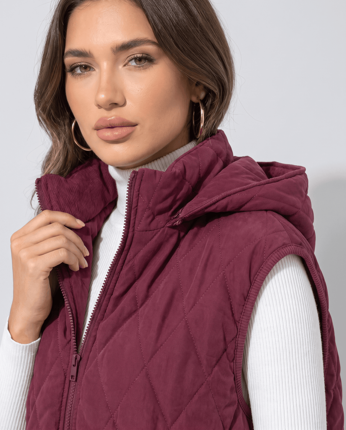 Burgundy hooded quilted vest with full zip front and attached hood, close view