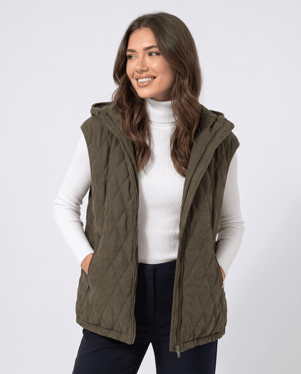 Green hooded quilted vest with hands in pockets, front view on a model