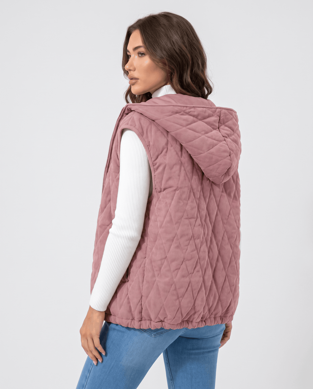 Back view of pink hooded quilted vest worn with blue jeans