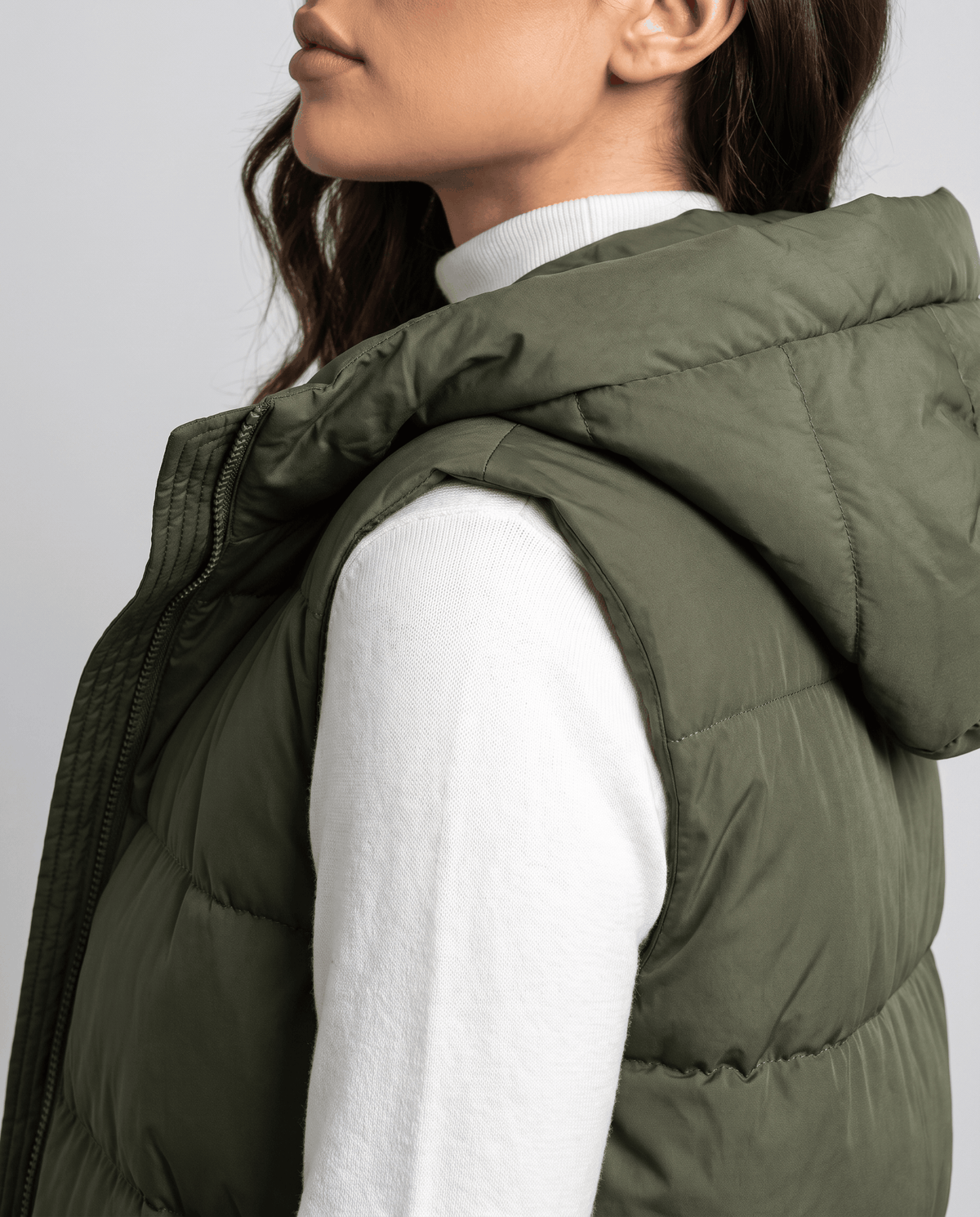 Side view of army green quilted vest hood and sleeveless armhole