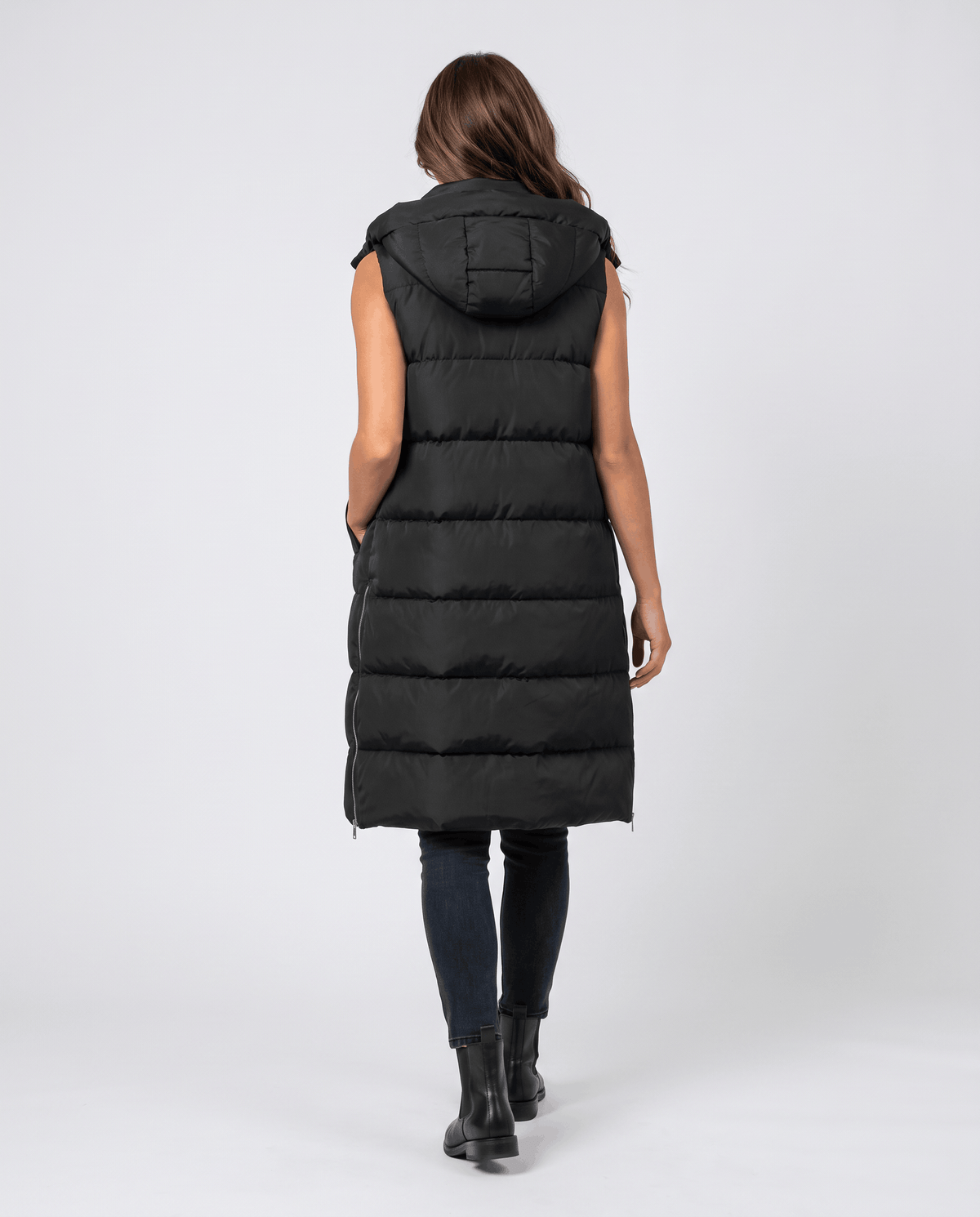 Back view of black knee-length hooded quilted vest with boots