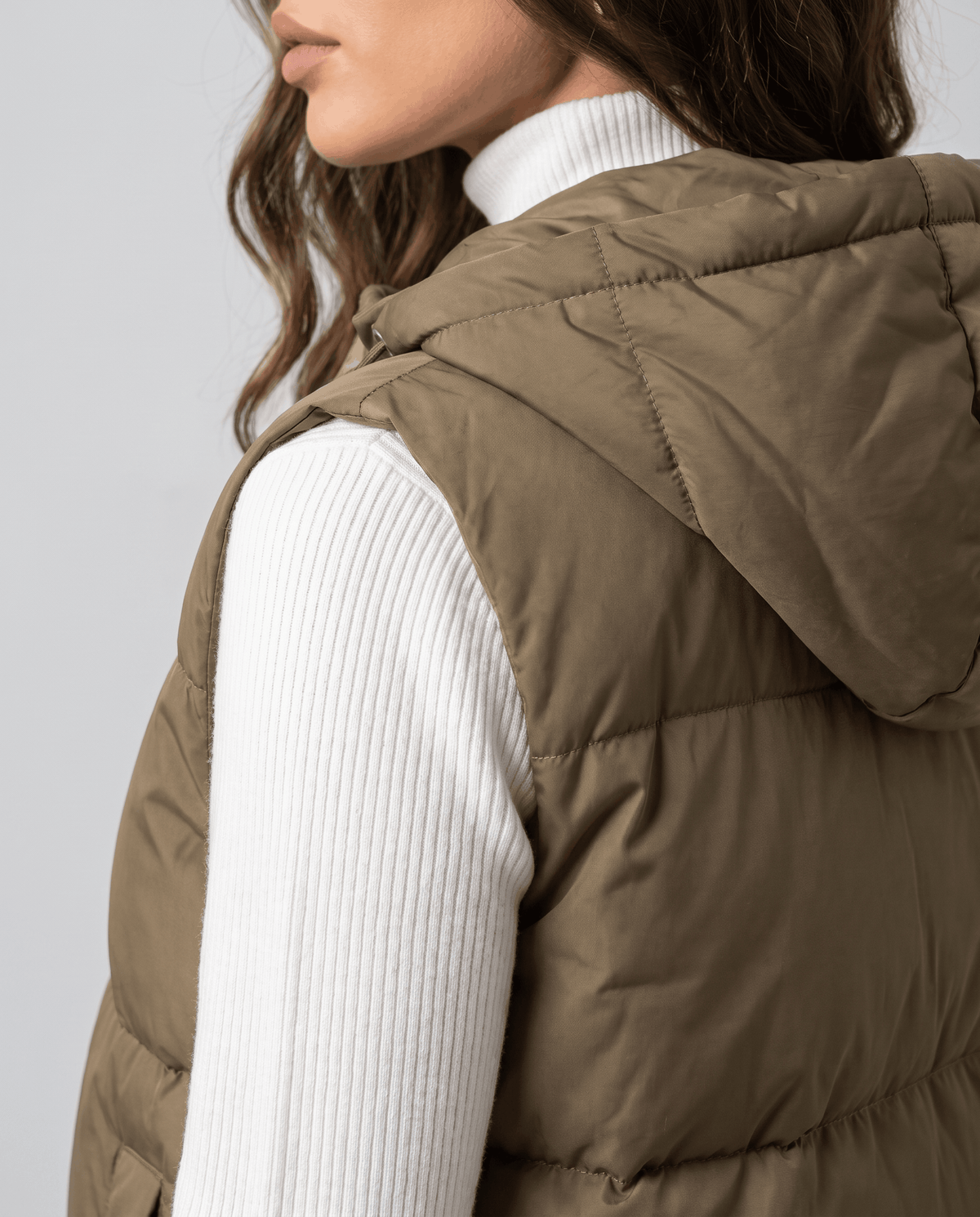Side view of khaki quilted vest hood and sleeveless armhole