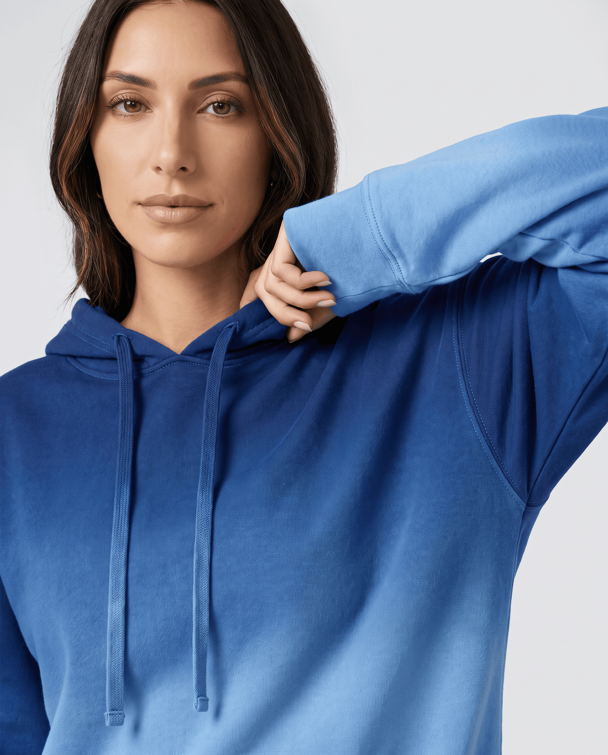 Close-up of the blue gradient hood, drawstrings and ribbed cuff with a hand at the sleeve