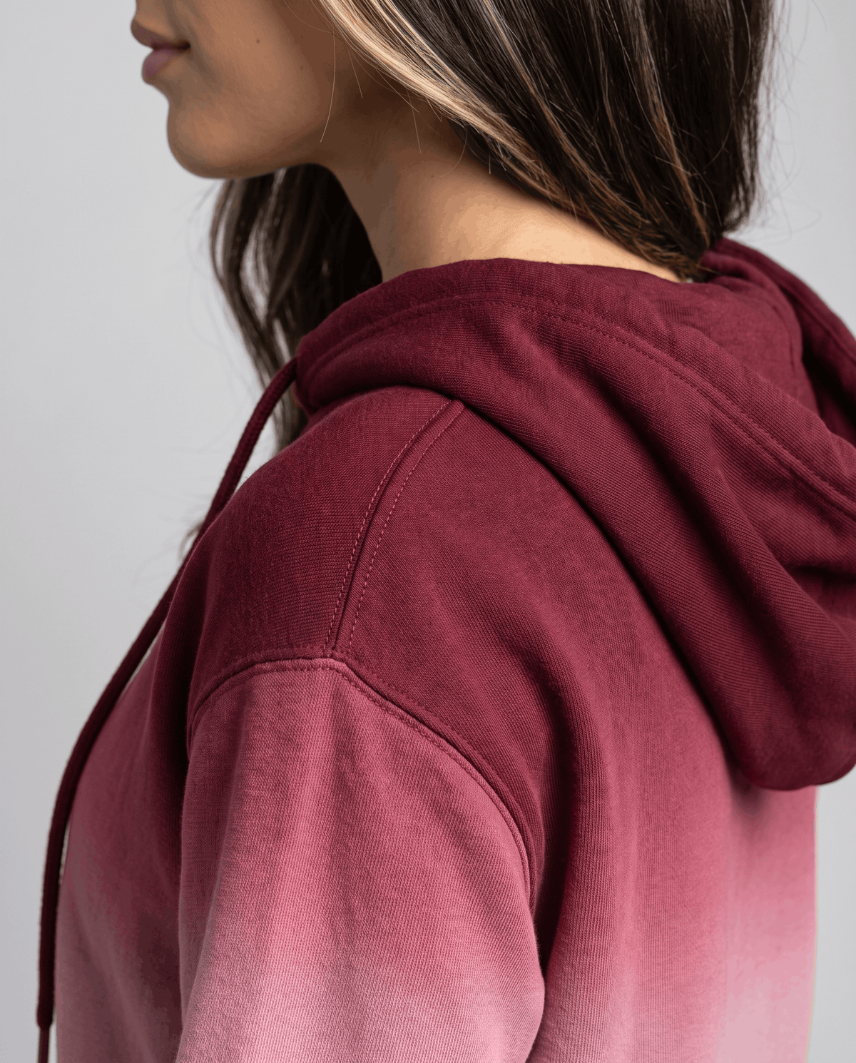 Side close-up of the burgundy hood and sleeve fading from deep red to pink