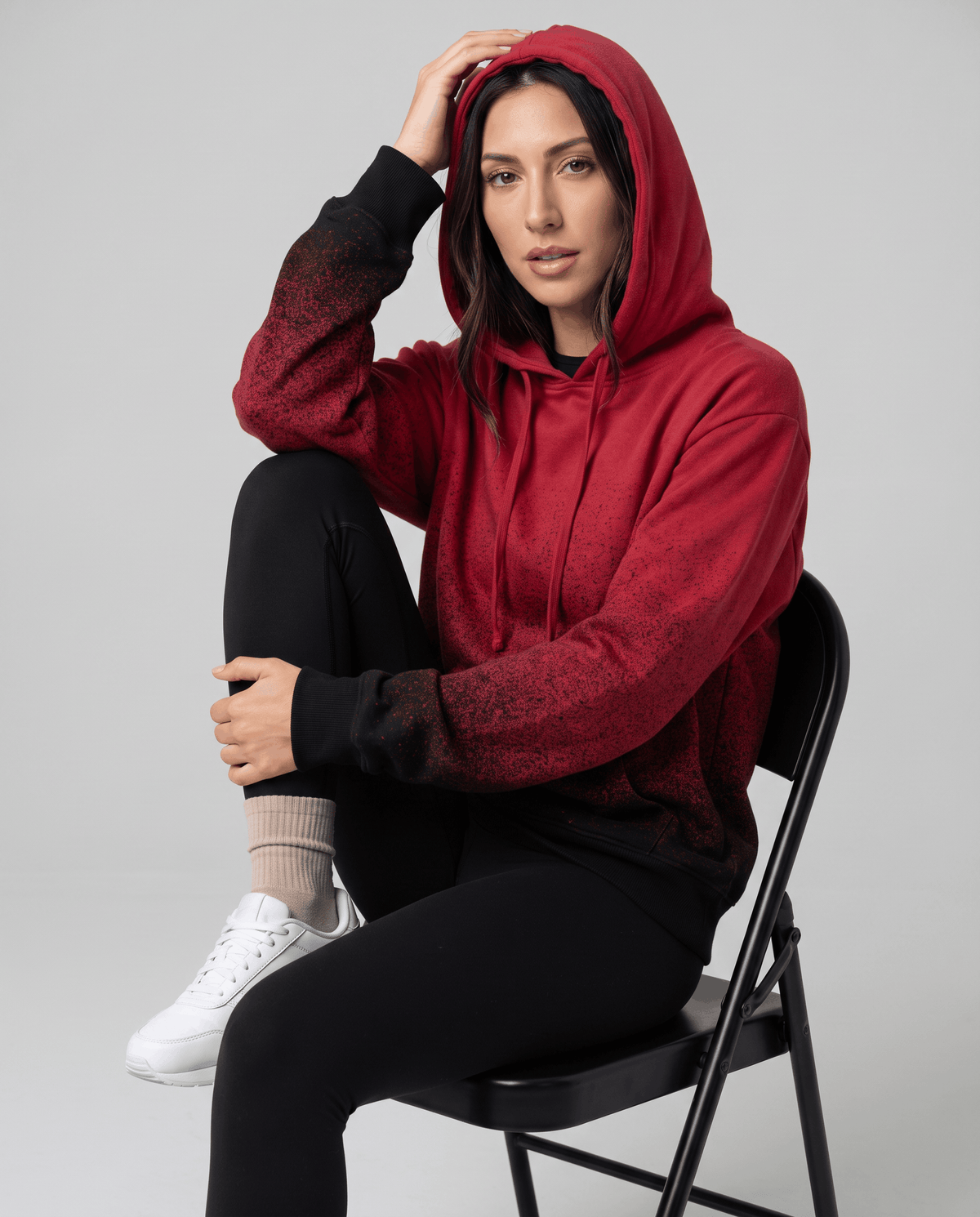 Seated look in the red hoodie with the hood up and a black faded hem